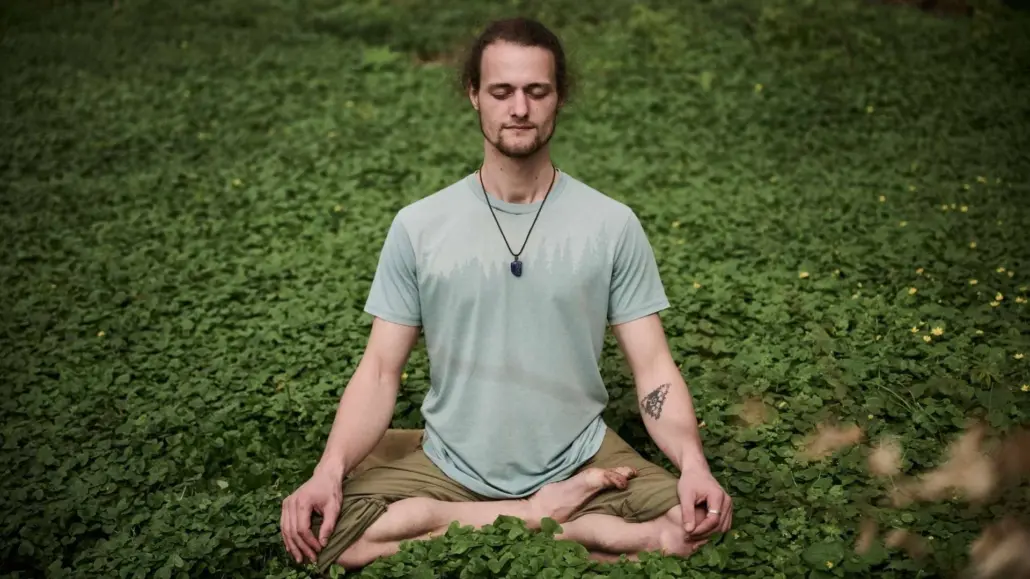 Moritz Waldner sitzt ruhig in der Natur und praktiziert bewusste Atemwahrnehmung.